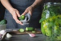 Woman preparing cucumbers for marinating with garlic and dill. Rustic dark style