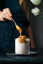 Scooping of dalgona coffee foam on top of the glass of milk