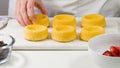 Woman preparing dessert, mini biscuit cups with strawberries and blueberries, close up on white background