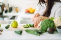 Woman preparing food in her kitchen. Female chopping fresh green vegetables on cutting board in light kitchen. Healthy Royalty Free Stock Photo