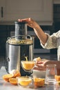 Woman preparing fresh orange juice for breakfast in kitchen.