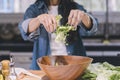 A woman preparing a green salad in her kitchen