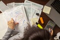 A woman is preparing her tax return in her office using forms calculator laptop and various notes