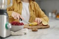 Woman preparing ingredients for tasty smoothie at white marble table in kitchen, closeup Royalty Free Stock Photo