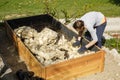 Woman preparing layers in a new raised garden bed: raw wool, branches and logs Royalty Free Stock Photo