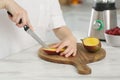Woman preparing mango for tasty smoothie at white marble table in kitchen, closeup Royalty Free Stock Photo