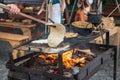 Woman preparing a natural flatbread on the open fire on the metal leaf during traditional annual medieval ages restoration.