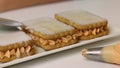 A woman is preparing pastries from cookies and cream. Drizzles cookies with milk to soften. Close-up shot