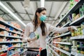 Woman preparing for pathogen virus pandemic spread quarantine.Choosing nonperishable food essentials.Budget buying at a supply Royalty Free Stock Photo