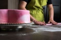 Woman preparing pink fondant for cake decorating, focus on the cake