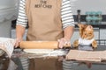 A woman before preparing pizza rolls out the dough on the kitchen table using a rolling pin Royalty Free Stock Photo