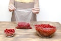 Woman preparing red currants in bowl for frozing in package at home kitchen for winter.peeling summer fruits, cooking Royalty Free Stock Photo