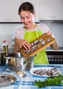 Woman preparing small fish indoors