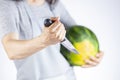 woman is preparing to stab a watermelon using a sharp kitchen knife.