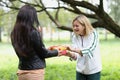 Woman presenting gift to friend in park