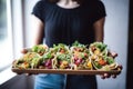 woman presenting multiple vegan tacos in a tray