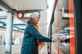 Senior woman press the button to open the door of the train Royalty Free Stock Photo