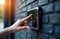 Woman presses button on modern digital system at brick wall entrance. Smart home security device allows access via code or Royalty Free Stock Photo