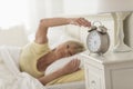 Woman Pressing Button Of Alarm Clock While Lying In Bed Royalty Free Stock Photo