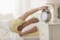 Woman Pressing Button Of Alarm Clock While Lying In Bed Royalty Free Stock Photo