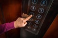 Woman pressing the button in the elevator interior