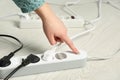 Woman pressing power button of extension cord on floor, closeup. Electrician`s