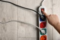 Woman pressing power button of extension cord on wooden floor, top view with space for text