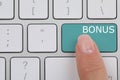 Woman pressing turquoise Bonus button on keyboard, closeup Royalty Free Stock Photo