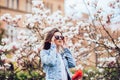 Woman or pretty girl posing at blossoming tree with magnolia flowers in spring garden on sunny day Royalty Free Stock Photo