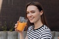 Woman with pretty smile holding in hand glass of refreshing orange drink, portrait closeup. Attractive girl drink tasty Royalty Free Stock Photo