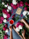 A woman in the process of making a summer bouquet of peonies, holds in her hand a cup of tea karkade. Tools and Royalty Free Stock Photo