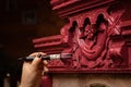 Woman in process of patination of wooden antique cupboard ornaments with big paint brush. Giving new life to old stuff Royalty Free Stock Photo