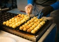 Woman process to cooking takoyaki at night maket. it most popular delicious snack of japan.