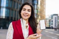 Woman professional business worker looking in camera and holding in hand mobile phone with empty mockup copy space screen Royalty Free Stock Photo