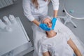 Woman professional doctor beautician applying mask on patient face for skin care