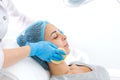 A woman, a professional doctor, a beautician cleanses the patient`s face with sponges before applying the mask for skin care