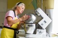 Woman professional pastry chef preparing a dessert. Adds ingredients and mixes the dough in a mixer