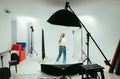 Woman professional photographer adjusts the light before shooting in a photo studio, rear view. Backstage