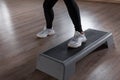 Woman professional trainer in stylish sports sneakers in leggings engaged in fitness on the platform step in the gym.