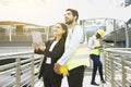 Woman project manager standing outside building and using tablet to discuss work with engineer coworker on construction site Royalty Free Stock Photo