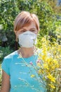 Woman in protection mask holding bouquet of wildflowers and trying to fight allergies