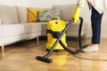 Woman in protective gloves cleaning the living room with yellow vacuum cleaner. Copy space. Clean concept Royalty Free Stock Photo
