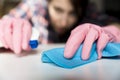 Woman in protective gloves is diligently cleaning white surface