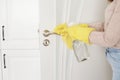 Woman in protective gloves disinfecting door handle while cleaning at home, close-up view on hands