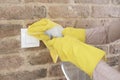 Woman in protective gloves disinfecting wall switches while cleaning at home, close-up view on hands Royalty Free Stock Photo