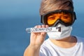 Woman in protective goggles and surgical mask holds abstract test tube with coronavirus