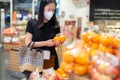 Woman in protective mask buying orange fruit supermarket.