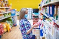 Woman in protective mask choosing detergents and cleaning products in supermarket. Royalty Free Stock Photo