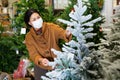 Woman in protective mask choosing New Year& x27;s tree in christmas street fair Royalty Free Stock Photo
