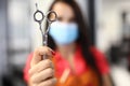 Woman in protective mask hold scissors in hand closeup.